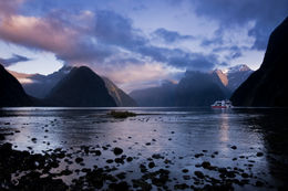 Photo of Overnight cruise to Milford Sound: Early morning ferry Ferry heading out into Milford Sound, New Zealand, as the clouds and mountain tops start to light up by the rising sun - December 2011