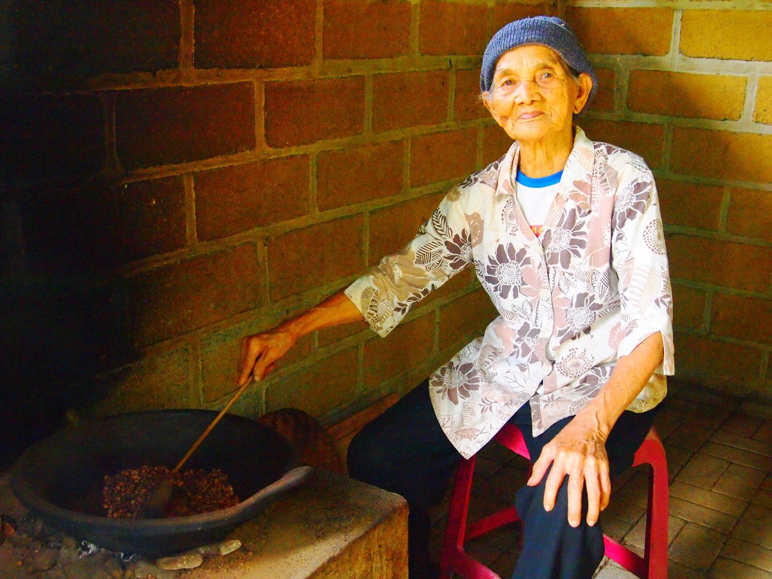 A Balinese lady stirring the Coffee beans