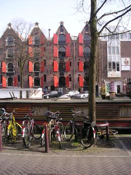 Photo of Bikes in front of a houseboat Another typical Amsterdam view. Bikes parked in front of a houseboat at a canal in the Jordaan in Amsterdam. In the background renovated 'pakhuizen'' warehouses that now are luxurious residential ... , Chou Fleur - September 2010